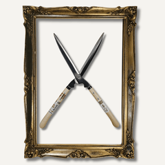 Crossed garden pruners inside an ornate gold frame on a white background