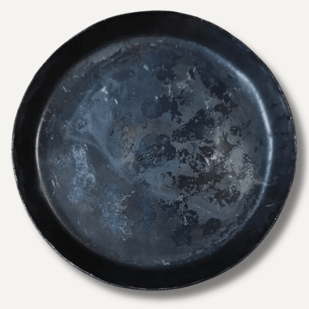 Black ceramic plate with a textured surface on a white background