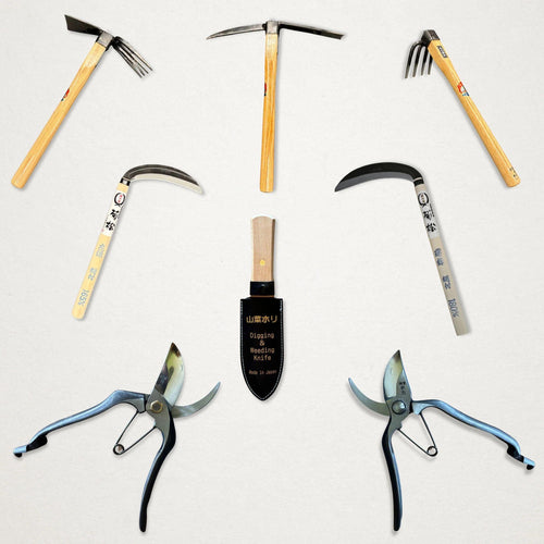 Japanese Azui hand hoes, sickles, hori hori knife and Tobisho pruning shears arranged on a light background.