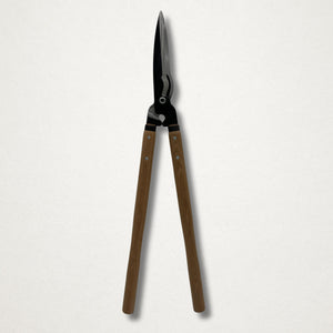 Full-length front view of Japanese hedge shears closed, with long wooden handles and black forged head on a white backdrop