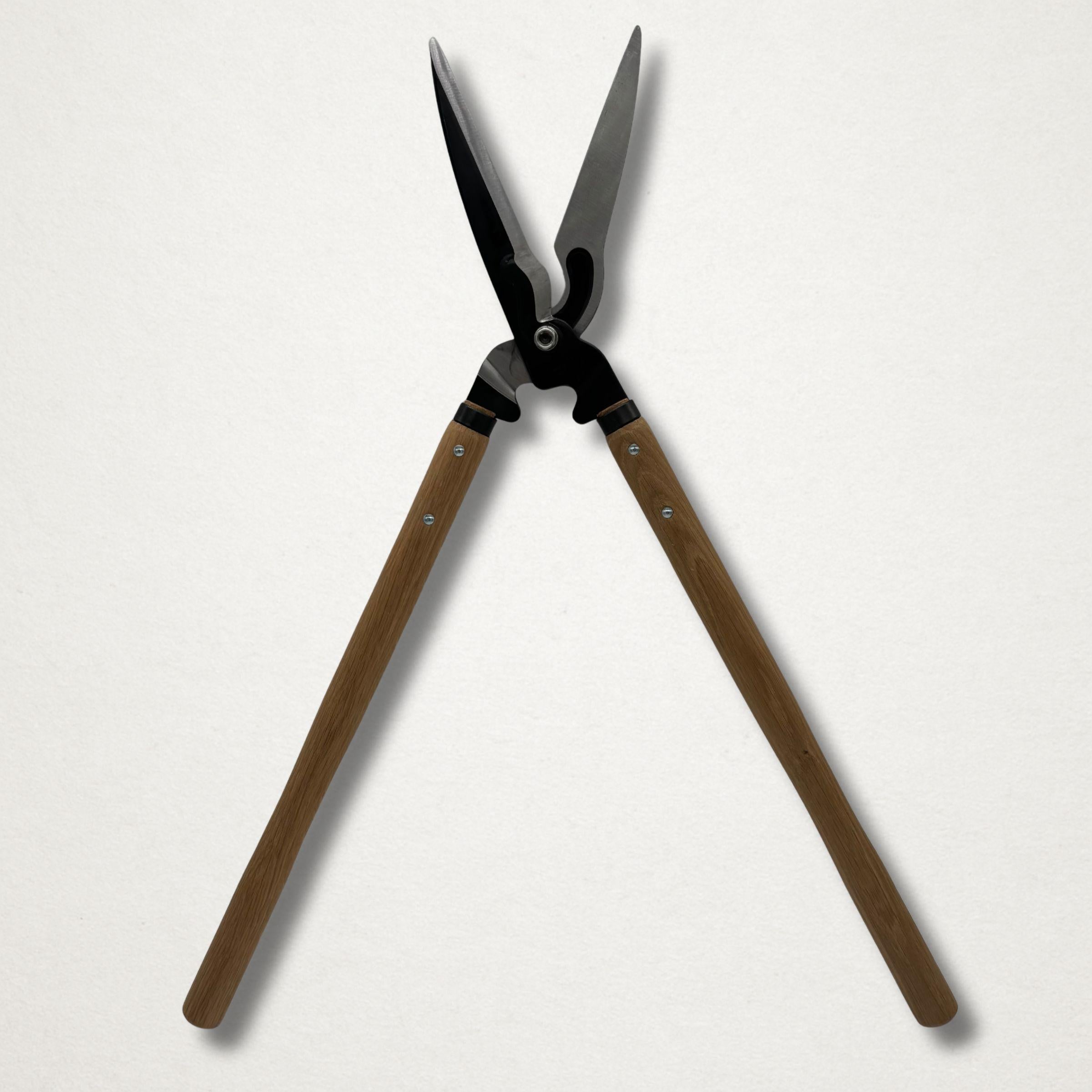 Full-length front view of Japanese hedge shears opened wide, showing long timber handles and black forged cutting head