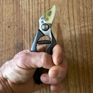 Hand holding Tobisho Hirei pruning shears, demonstrating handle shape and ergonomic fit