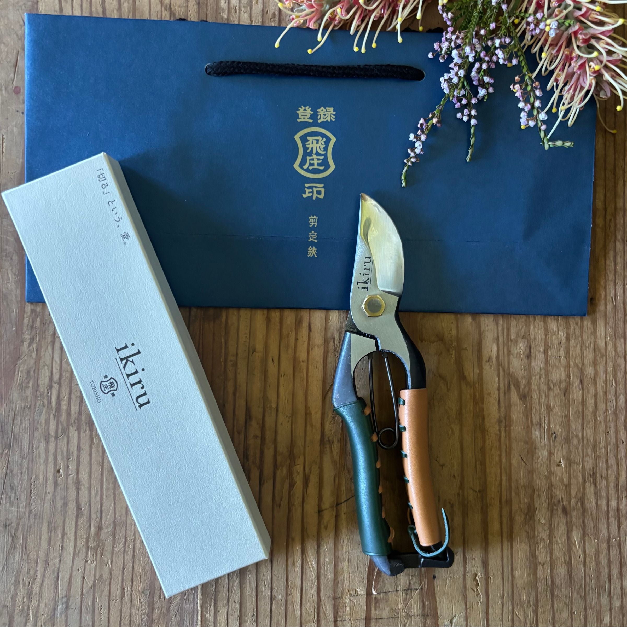 Ikiru secateurs with flowers, box, and Tobisho bag – styled photo with gift packaging and floral accent for presentation.