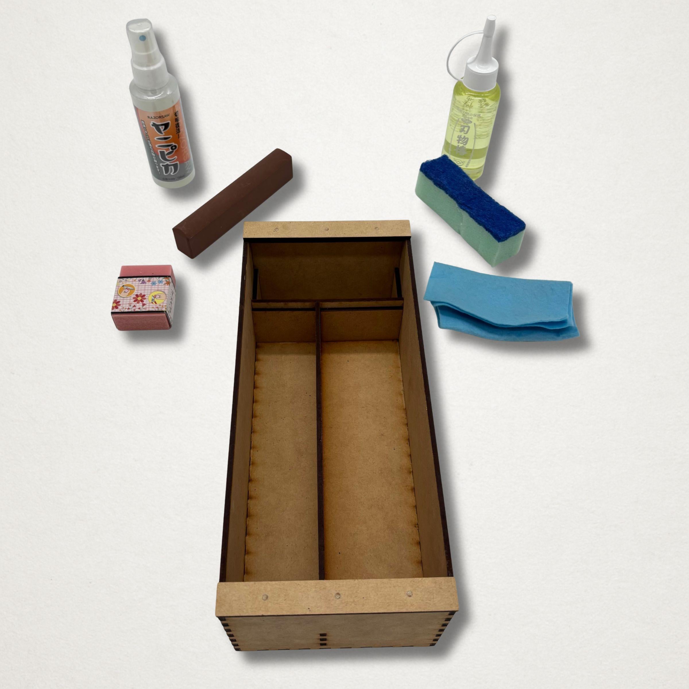 Japanese garden tool maintenance kit contents laid out beside a handmade wooden storage box, including camellia oil, blade cleaner, cloth, rust eraser and sharpening stone.