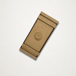 Closed handmade wooden toolbox for a Japanese garden tool maintenance kit, with an engraved East West Tools logo on the sliding lid.