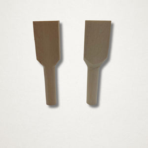 Pair of hinoki teaspoon carving blanks standing upright on a white background