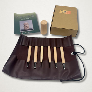 Michi Hamono Little Jizo carving kit laid out with tool roll, carving tools, instruction booklet, wood blank, and box