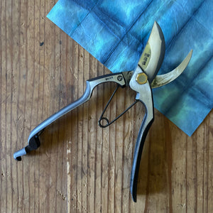 Open Tobisho Yasugi blue steel Type-A pruning shears on indigo washi paper, showing Yasugi Blue Steel blade