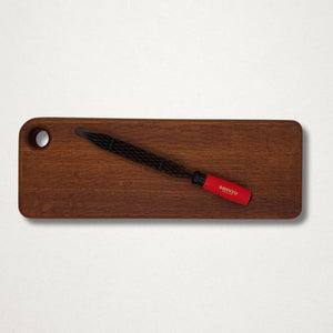 Shinto saw rasp with red handle laid diagonally on a sheoak wooden board against a light grey background