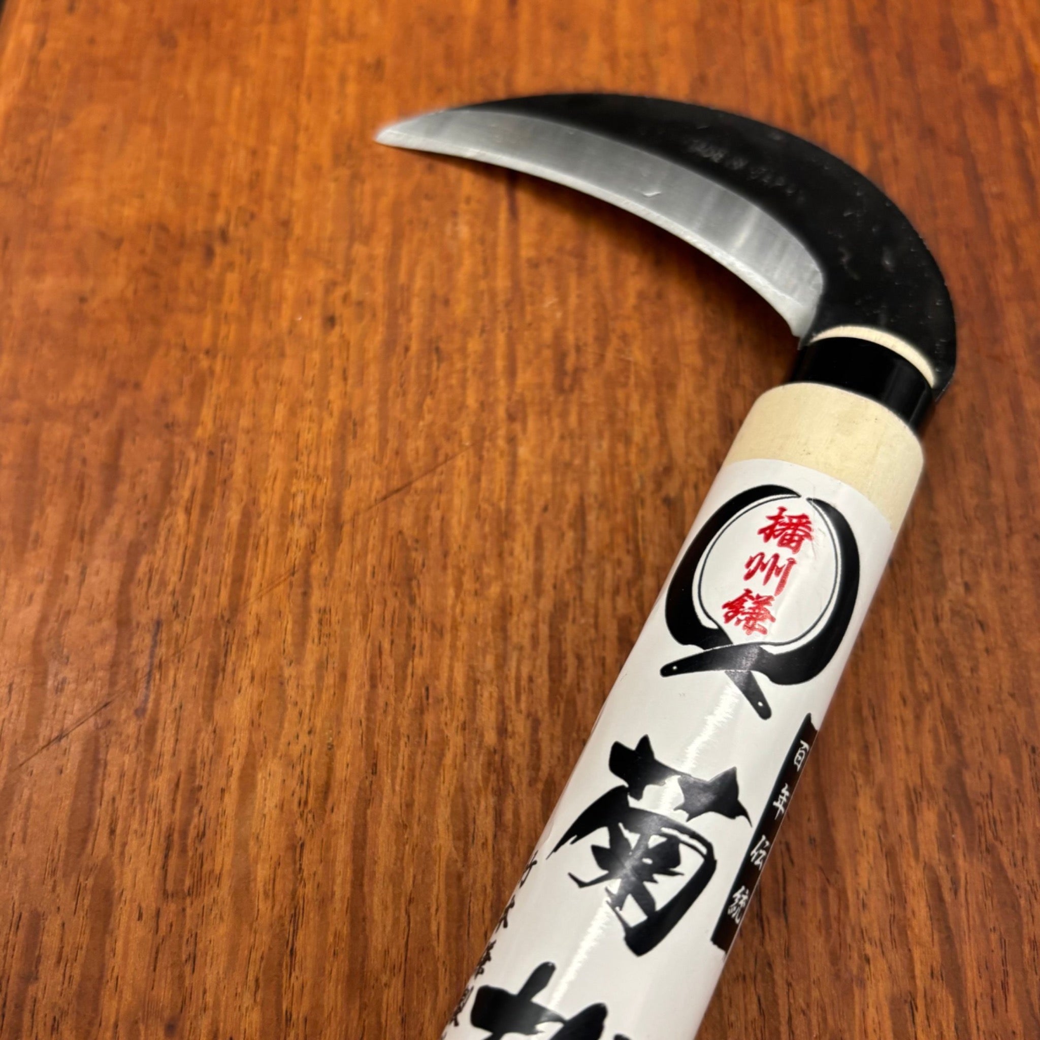 Takemoto Kikumatsu mulberry sickle 90mm blade and maker label detail on wooden board