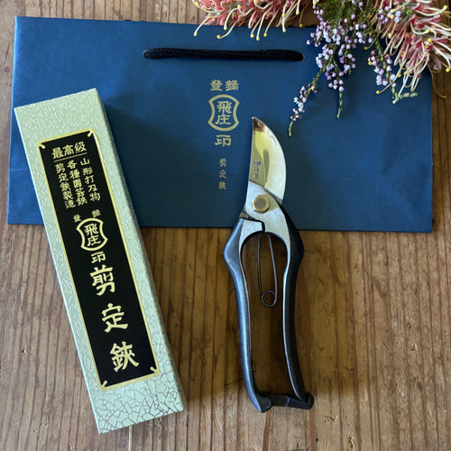 Tobisho Classic Type-A 200 mm pruning shears with gift box and blue bag, displayed on wooden surface with flowers