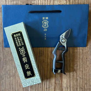 Tobisho Hirei pruning shears beside box and bag, shown closed on wooden surface