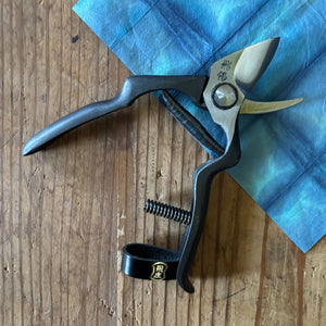 Tobisho Hirei pruning shears open, showing blade shape and cutting geometry on blue washi paper