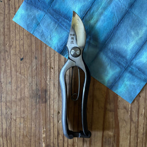Tobisho Type-B 180mm Japanese pruning shears closed on blue cloth background, Yasugi steel with traditional metal catch lock, Yasugi steel with traditional metal catch lock