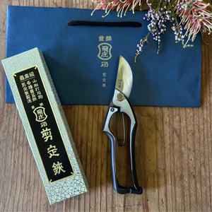 Tobisho Yasugi steel Type-A 200mm Japanese pruning shears on blue bag with box and flowers