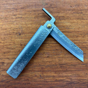 Top view of a Japanese higo knife partly opened, with hammered metal handle and kiridashi-style blade on wood