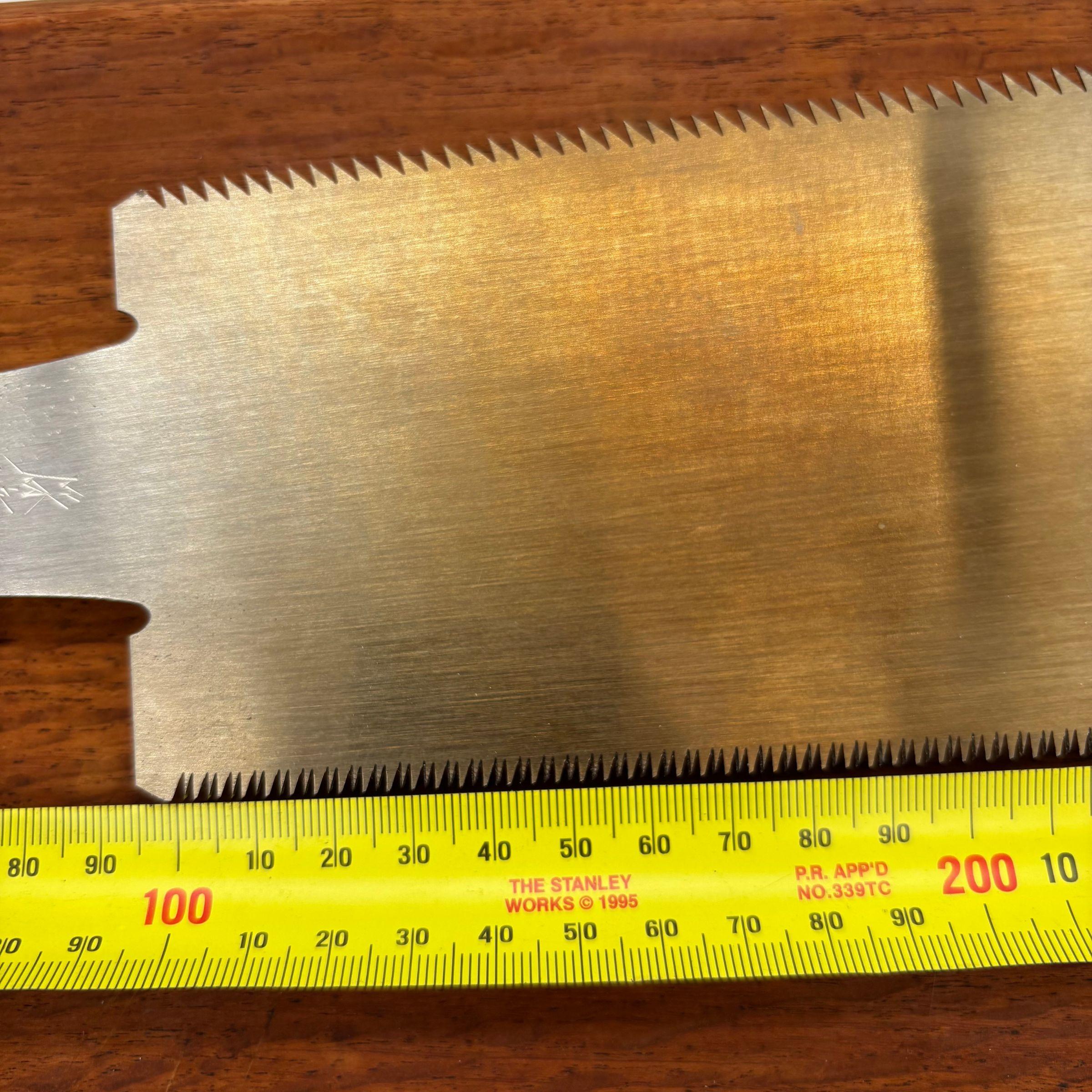 Close-up of a Japanese saw blade with ruler showing tooth spacing and blade width