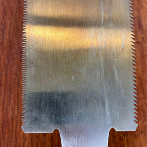 Close-up of the lower blade and tooth line of the Japanese saw on timber board