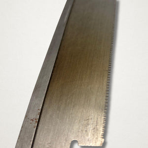 Close-up of vintage Japanese 240mm dozuki saw blade showing fine joinery teeth and hand-finished steel surface.