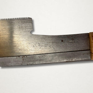 Close-up of vintage Japanese 240mm dozuki saw near the tang showing age marks, forge-welded construction, and carbon steel blade detail.