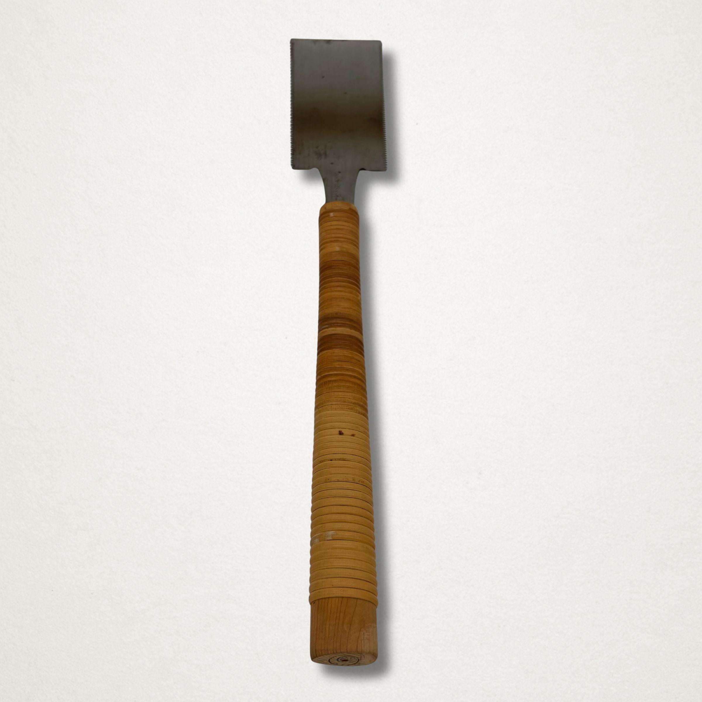 Reverse view of a vintage Japanese ryoba saw with cane-wrapped handle, photographed vertically against a white background