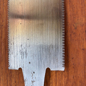 Close-up of the upper section of a vintage Japanese ryoba saw blade showing fine surface spotting, horizontal grind marks and dual toothlines