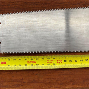 Close-up of 210mm Japanese ryoba saw blade beside tape measure showing full cutting length