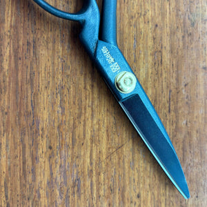 Close-up of black Masamune tailor scissors blade and pivot on timber surface
