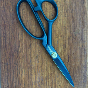Black Japanese tailor scissors closed on timber surface, full product view