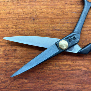 Close-up of black Japanese tailor scissors pivot and blade on timber surface